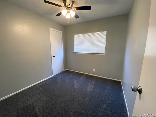 an empty room with a window and a fan
