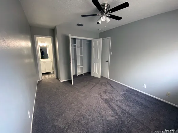 an empty room with closet and a ceiling fan