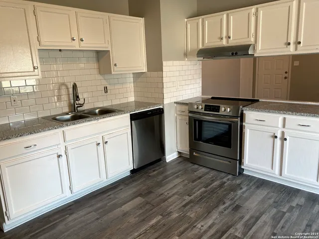 a kitchen with granite countertop white cabinets and white appliances