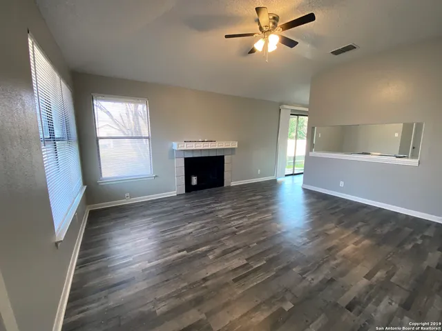 a view of empty room with wooden floor and fan