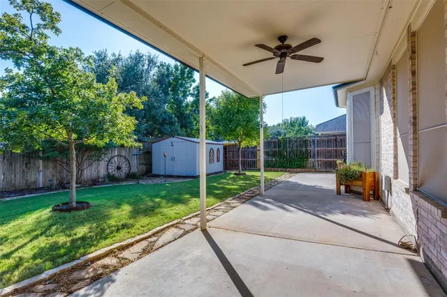 a view of a backyard with couches plants and large tree
