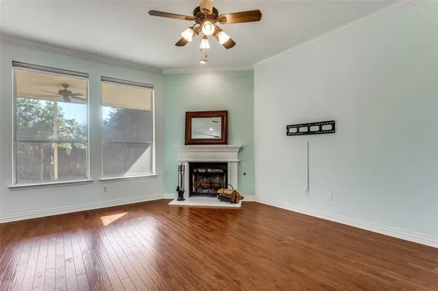 a view of an empty room with wooden floor fireplace and a window
