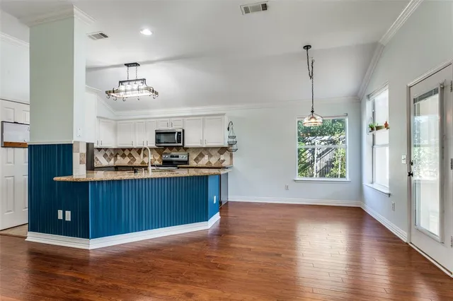 a kitchen with stainless steel appliances granite countertop a refrigerator a sink dishwasher and wooden floor