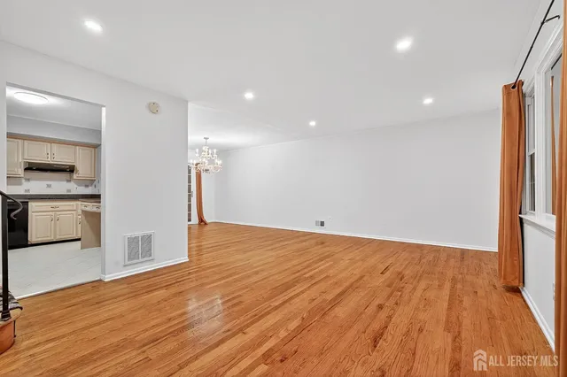 a view of an empty room with wooden floor and stairs