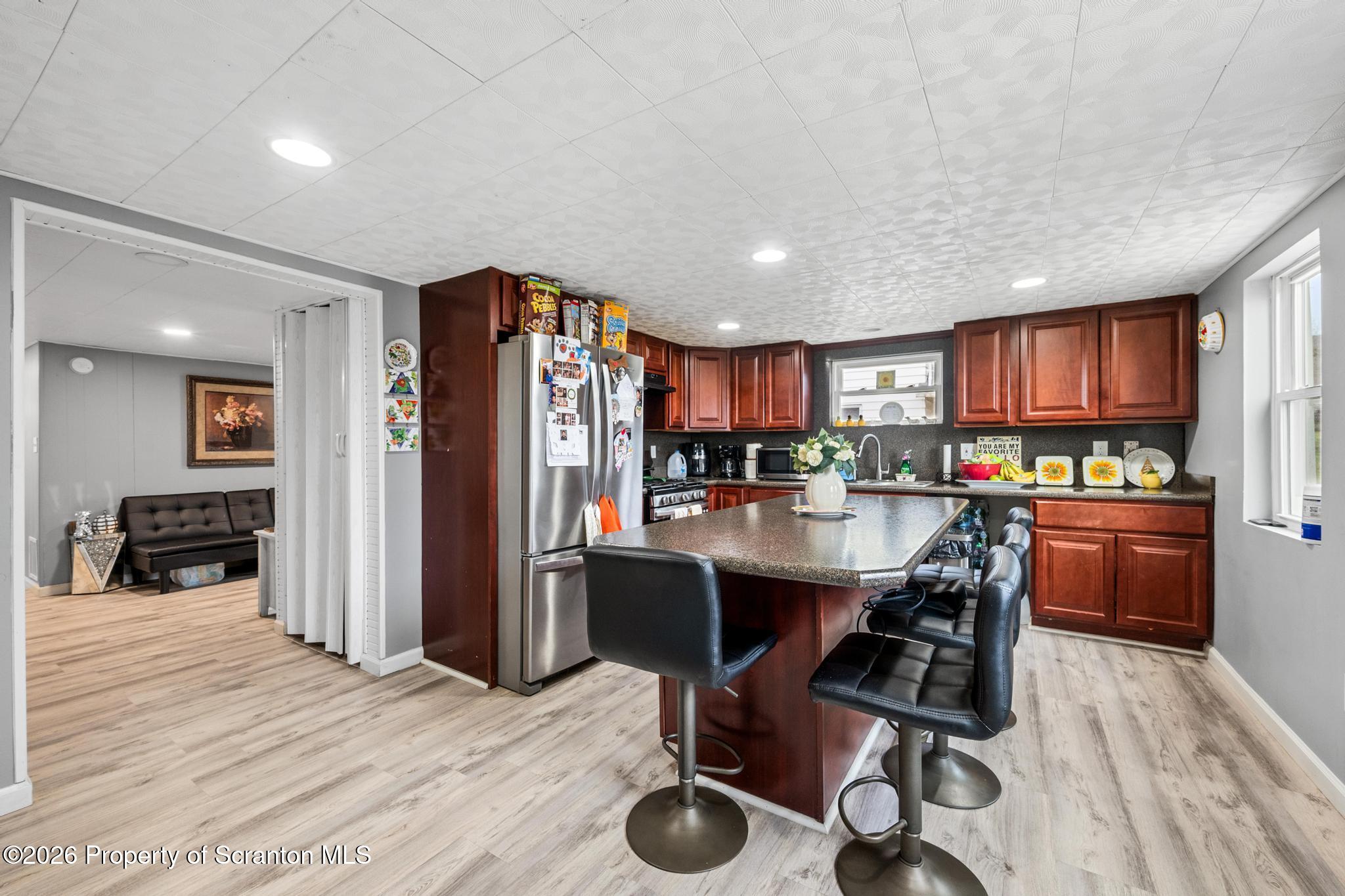 1227 Bennett Street Old Forge, PA 18518 - Photo 8 of 26 a kitchen with stainless steel appliances granite countertop a refrigerator a stove a sink dishwasher and a dining table with wooden floor