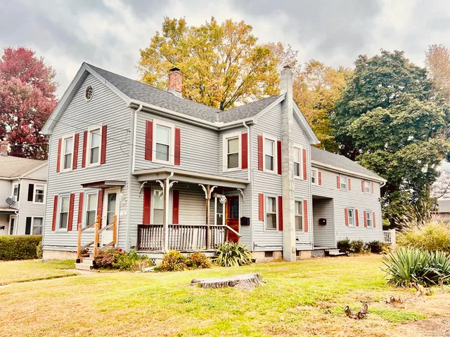 a view of a white house with a large tree in front of it