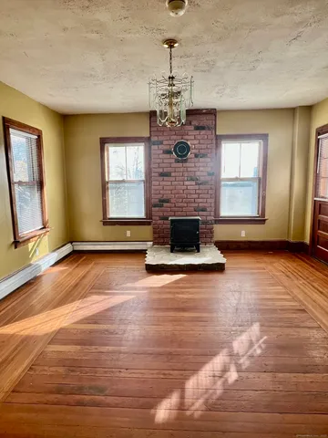 a view of a livingroom with a fireplace a chandelier and windows