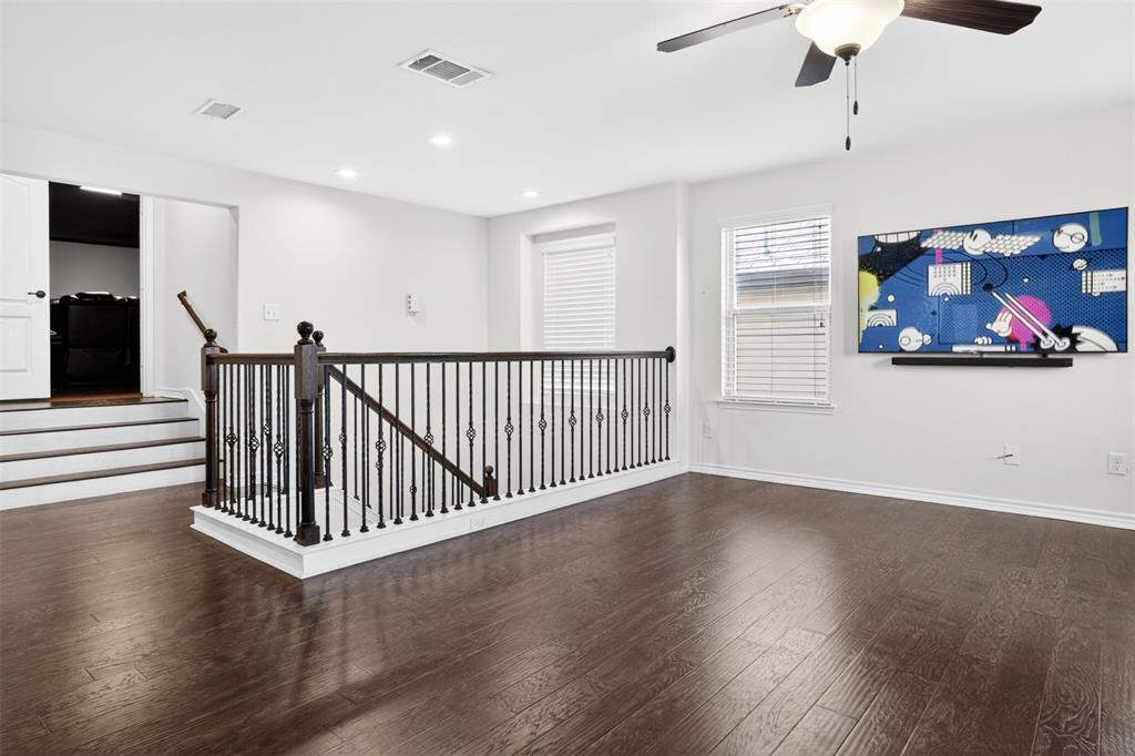 8728 Maple Ridge Trail Fort Worth, TX 76244 - Photo 25 of 40 Spacious loft area featuring dark wood-finish flooring, decorative wrought iron railing, and white interior paint