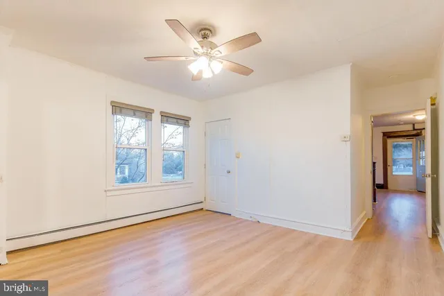 an empty room with wooden floor chandelier fan and windows
