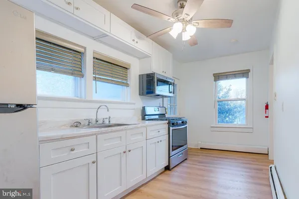 a kitchen with stainless steel appliances granite countertop a sink cabinets wooden floor and a window