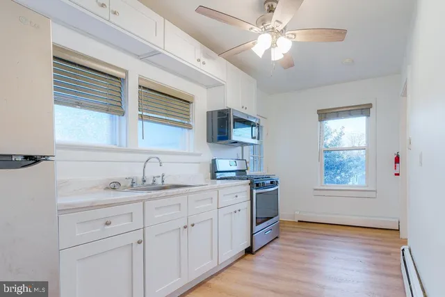 a kitchen with stainless steel appliances granite countertop a sink cabinets wooden floor and a window