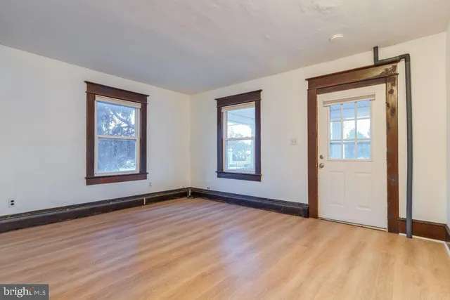 a view of an empty room with window and wooden floor