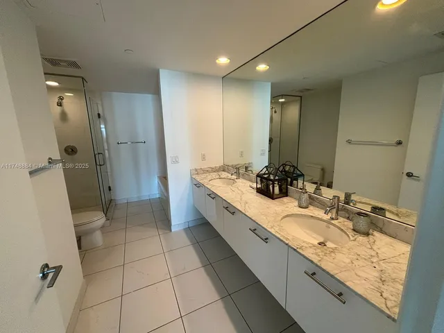 a bathroom with a double vanity sink toilet and shower