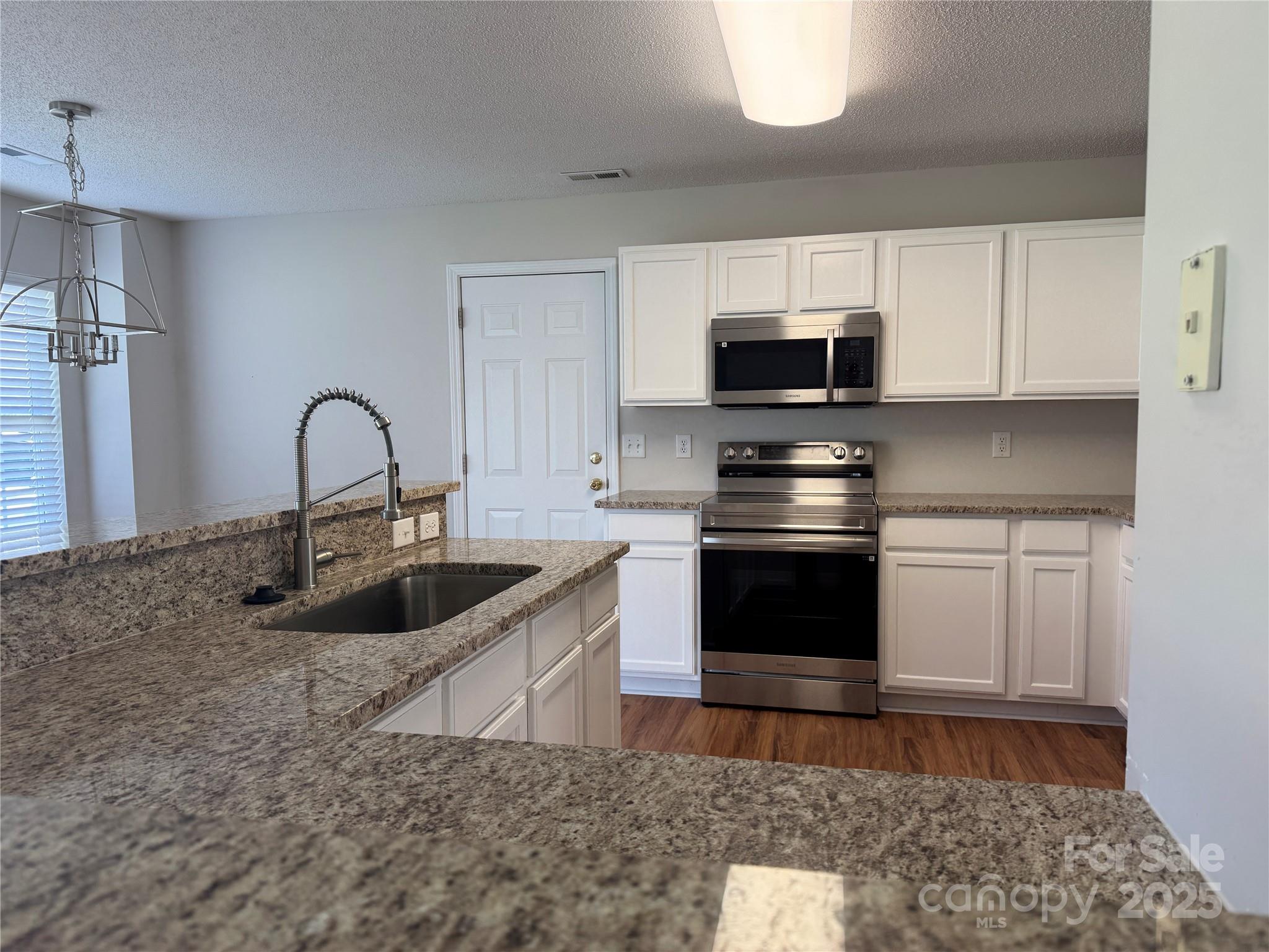 5506 Rogers Road Indian Trail, NC 28079 - Photo 11 of 30 a kitchen with granite countertop a sink and a stove top oven