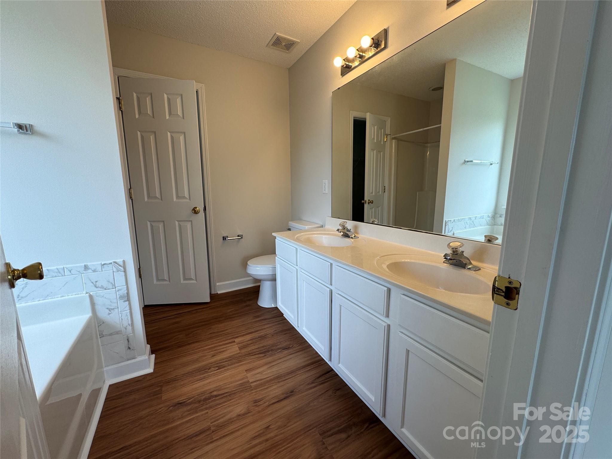 5506 Rogers Road Indian Trail, NC 28079 - Photo 21 of 30 a bathroom with a double vanity sink and mirror with wooden floor