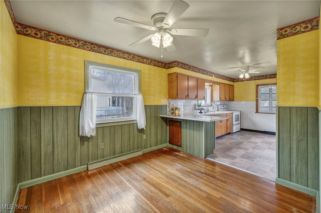 367 High Grove Boulevard Akron, OH 44312 - Photo 11 of 46 Kitchen featuring a baseboard radiator, a ceiling fan, light wood-style floors, a peninsula, and white electric stove