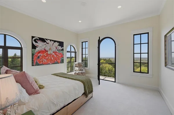 a bedroom with a bed a painting on the wall and a window