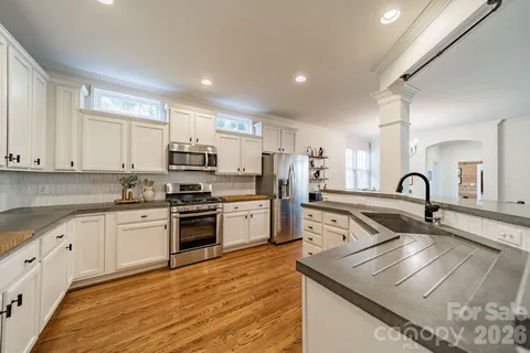 a kitchen with stainless steel appliances granite countertop a sink and white cabinets