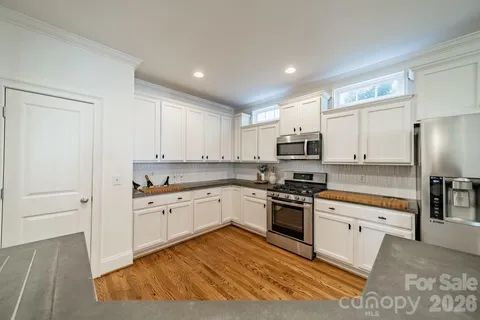 a kitchen with granite countertop white cabinets and stainless steel appliances
