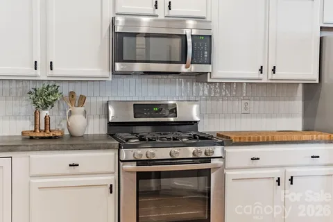 a kitchen with stainless steel appliances granite countertop white cabinets and a stove