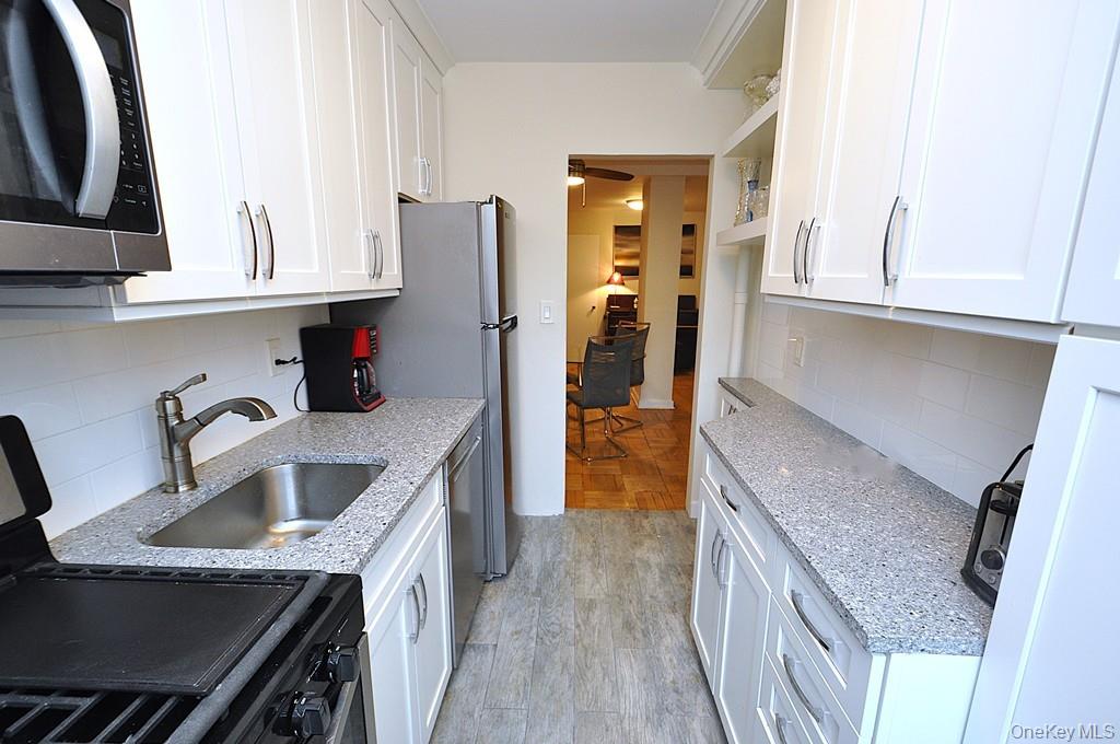 235 Garth Road, Unit A5B Scarsdale, NY 10583 - Photo 11 of 47 a kitchen with stainless steel appliances granite countertop a sink and a refrigerator