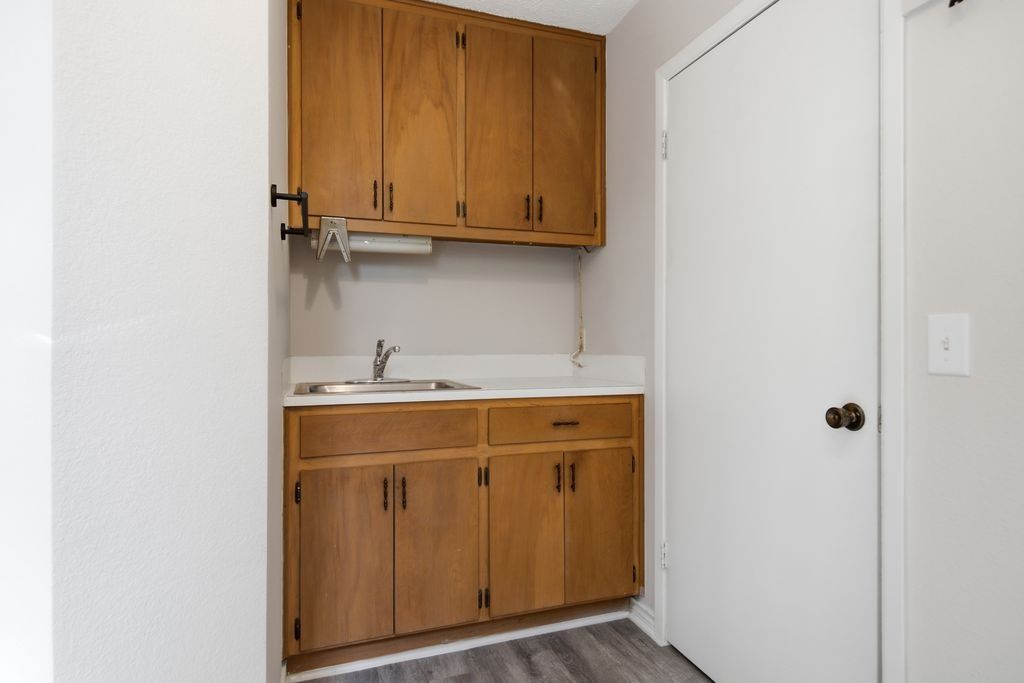 1454 Red Town Road Elgin, TX 78621 - Photo 11 of 40 A compact laundry space with wood cabinetry and a utility sink offers practical functionality.
