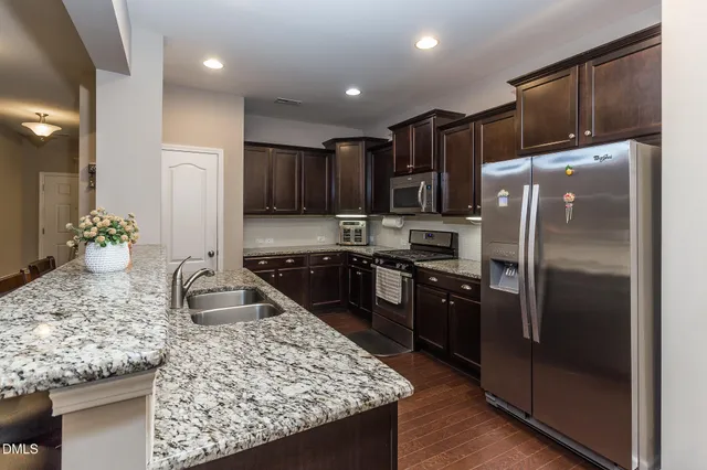 a kitchen with kitchen island granite countertop a refrigerator a stove and a sink
