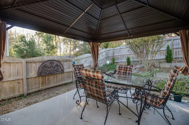 a view of patio with table and chairs under an umbrella with a small yard