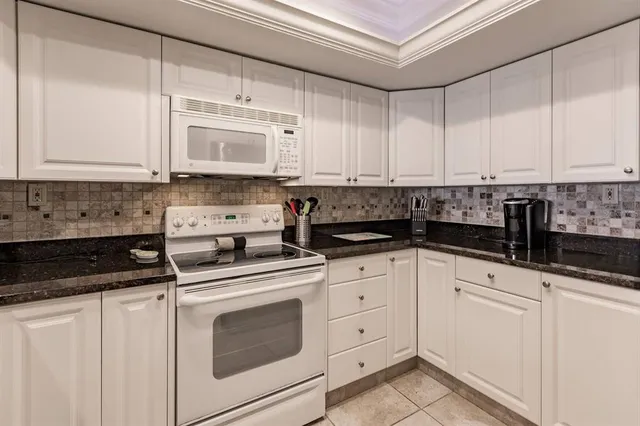 a kitchen with granite countertop white cabinets and white appliances