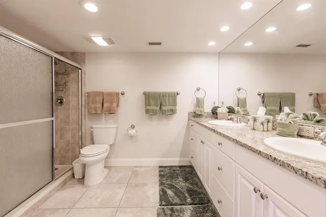 a bathroom with a granite countertop sink a toilet a mirror and shower