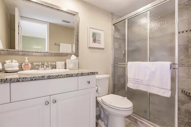 a bathroom with a granite countertop toilet sink and mirror