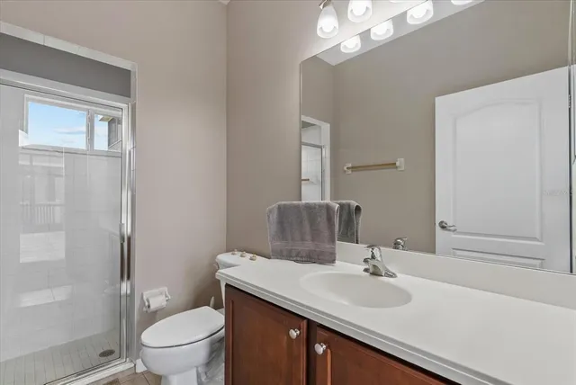 a bathroom with a toilet a sink a mirror a vanity and shower