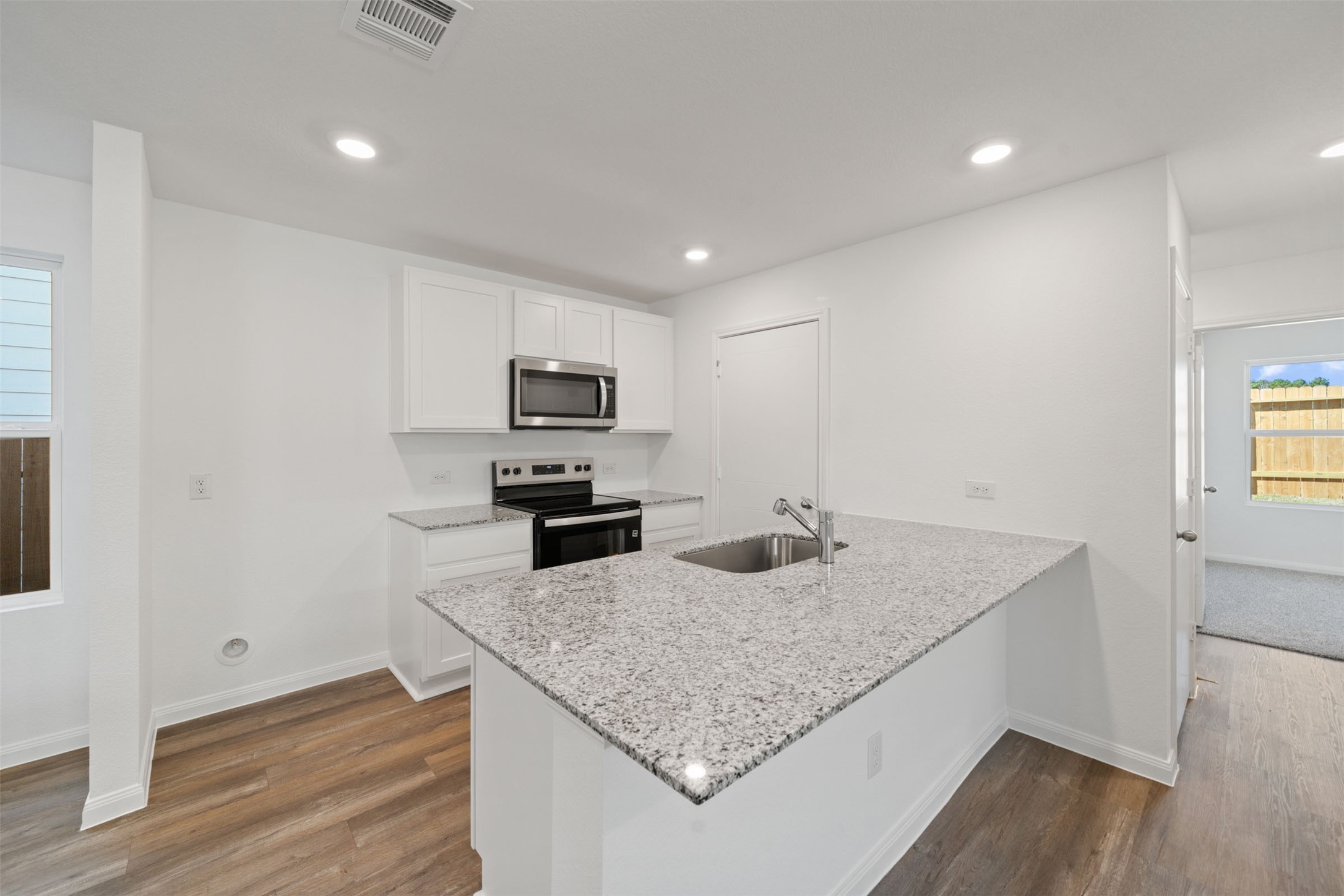 12327 Sword Point Court Willis, TX 77378 - Photo 17 of 30 a kitchen with stainless steel appliances granite countertop a sink a microwave counter space and wooden floor