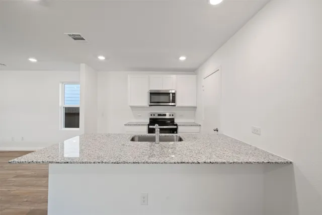 a kitchen with granite countertop a sink a stove and a microwave