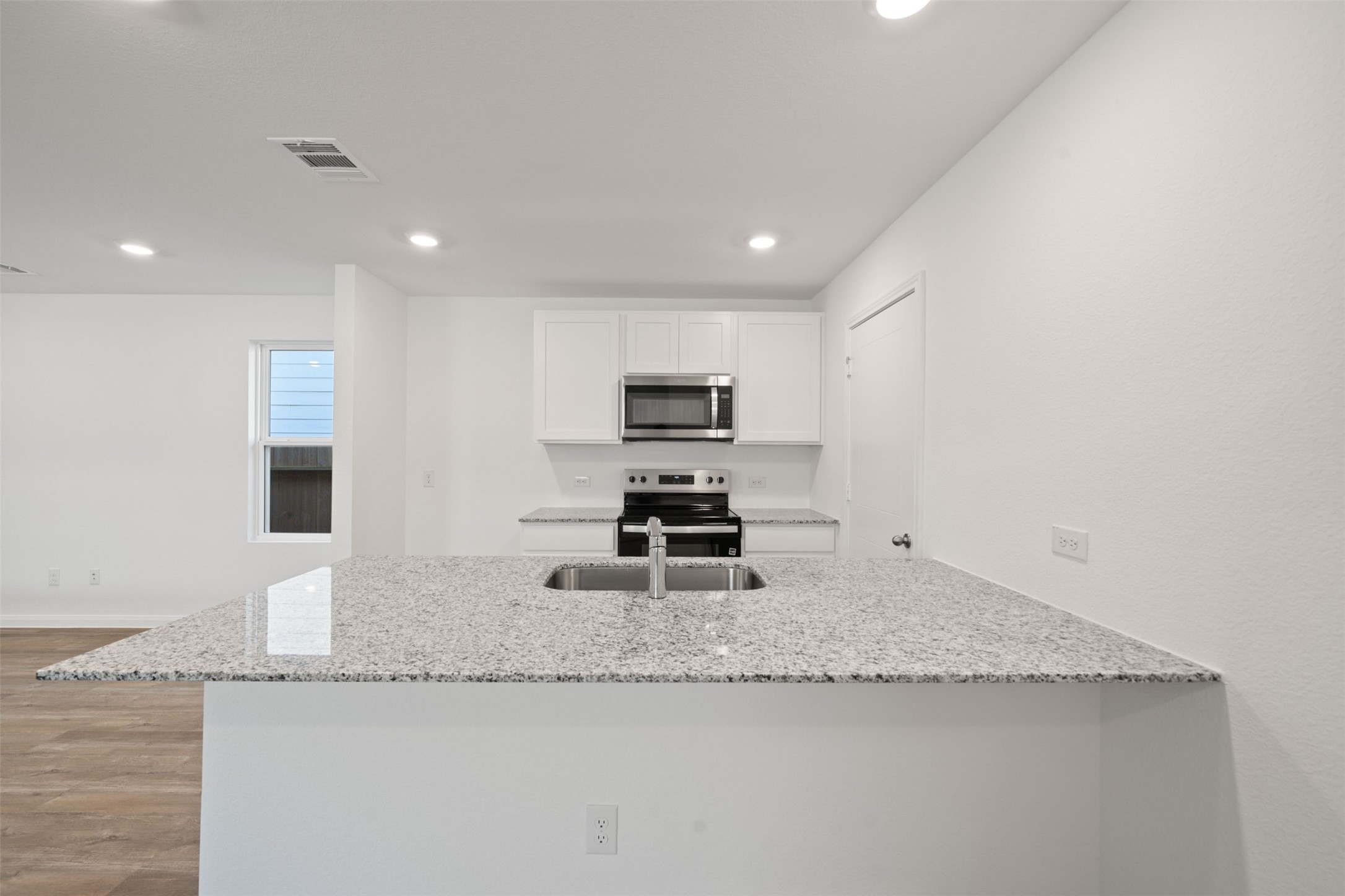 12327 Sword Point Court Willis, TX 77378 - Photo 18 of 30 a kitchen with granite countertop a sink a stove and a microwave