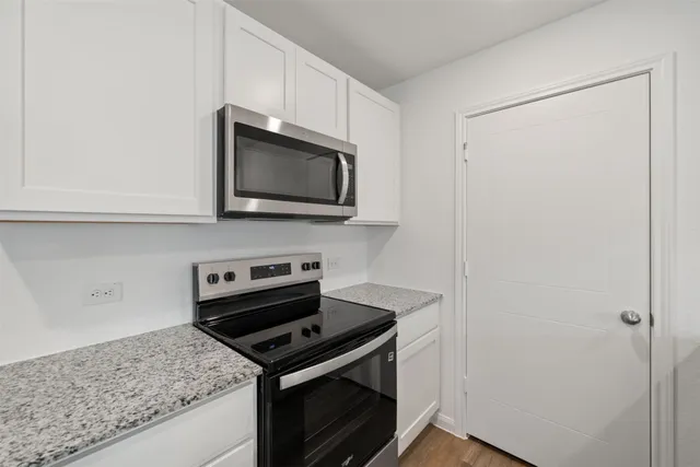 a kitchen with granite countertop cabinets stainless steel appliances and a wooden floor