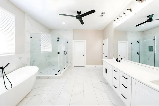 a spacious bathroom with a double vanity sink a toilet a mirror and shower