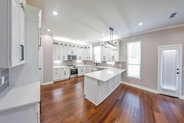 a large kitchen with a center island wooden floor stainless steel appliances and a window