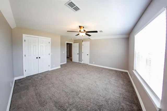 an empty room with a ceiling fan and a window