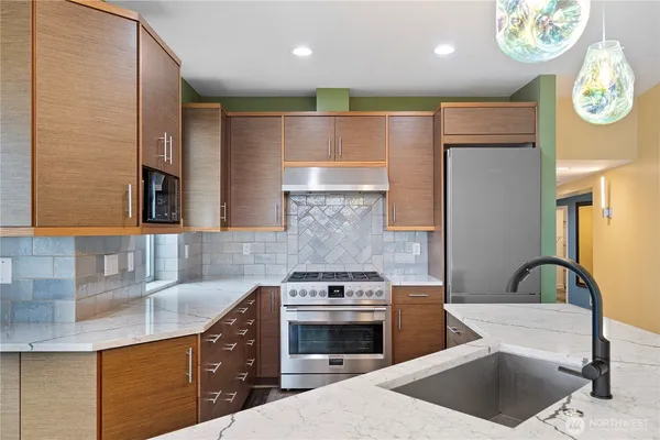 a kitchen with kitchen island granite countertop a sink and a refrigerator