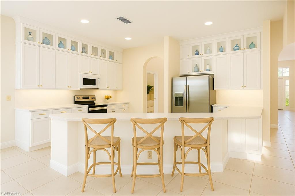 2451 Game Hawk Court, Unit 2502 Naples, FL 34105 - Photo 3 of 30 a kitchen with stainless steel appliances kitchen island granite countertop a refrigerator and microwave