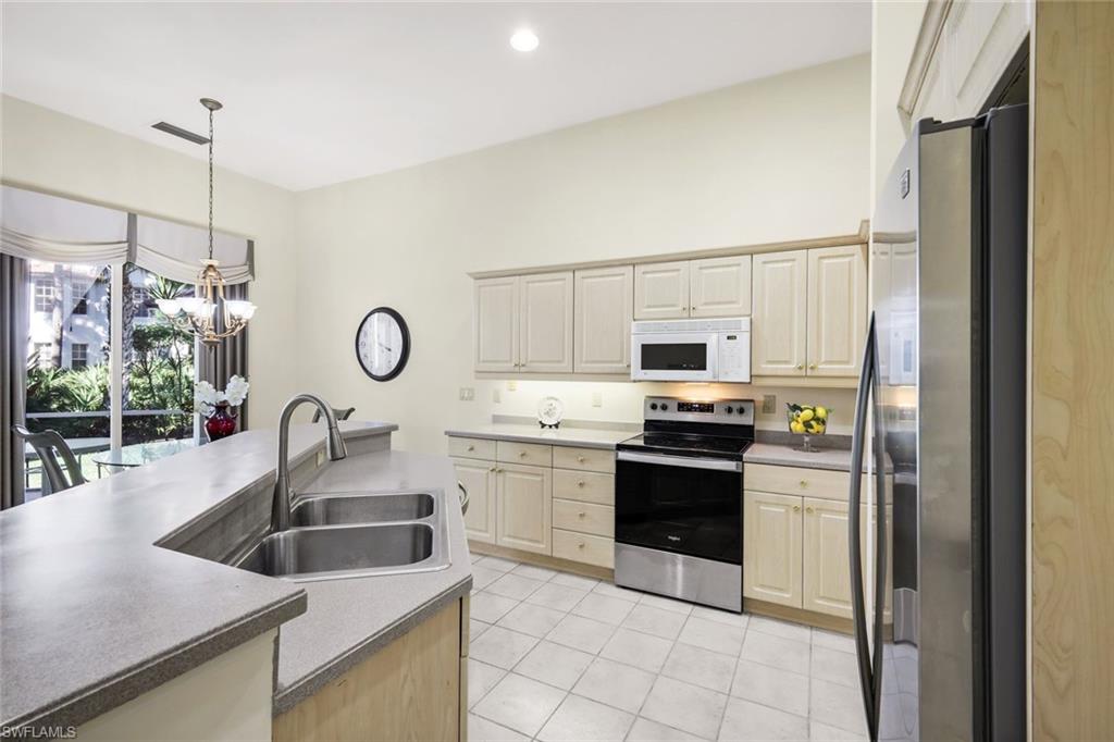 2451 Game Hawk Court, Unit 2502 Naples, FL 34105 - Photo 6 of 30 a kitchen with stainless steel appliances granite countertop a sink a stove and a refrigerator with wooden floor
