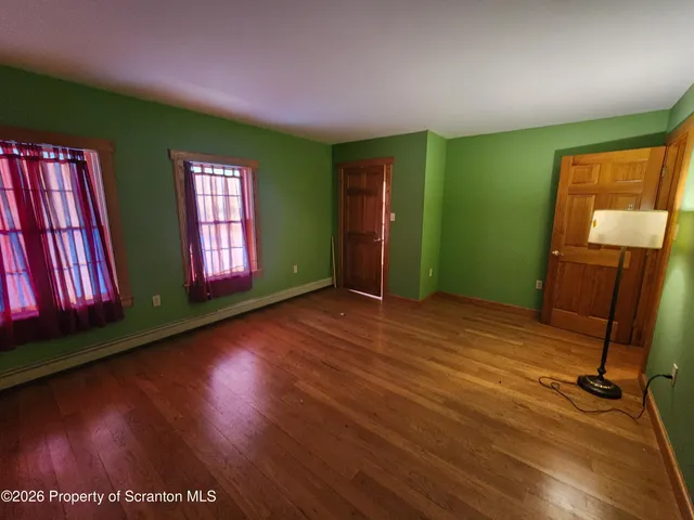 a view of an empty room with window and wooden floor
