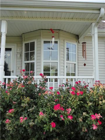 Home is surrounded by beautiful landscaping and shows an elegant bay window.