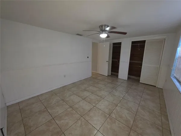 an empty room with closet and a ceiling fan