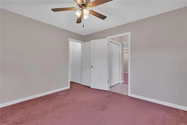 an empty room with closet and a chandelier fan