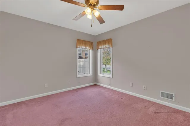an empty room with windows and chandelier fan