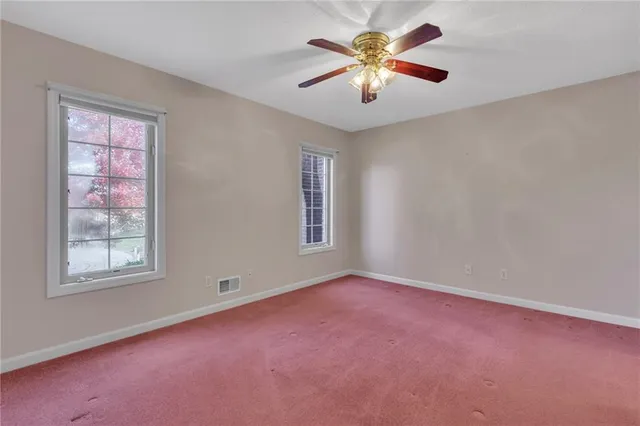 an empty room with windows and chandelier fan