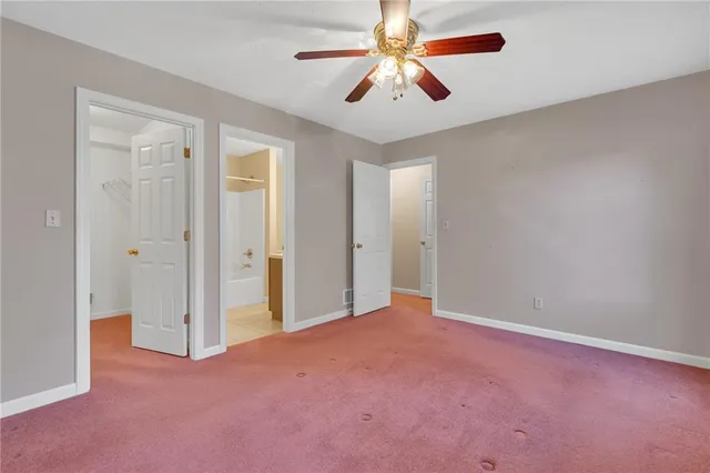 an empty room with chandelier fan and windows