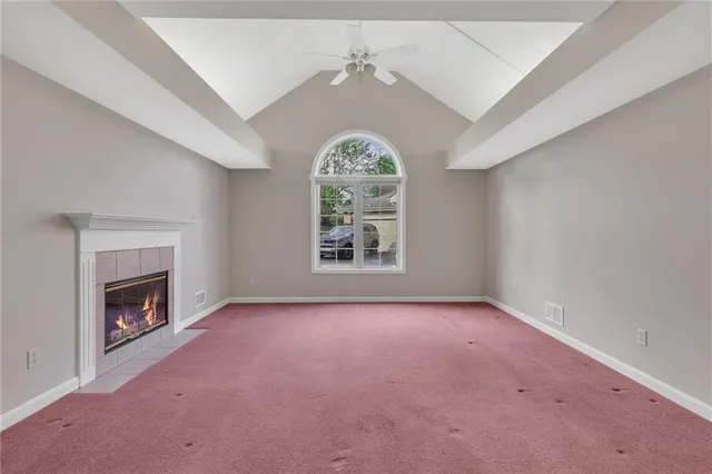 an empty room with windows fireplace and fans
